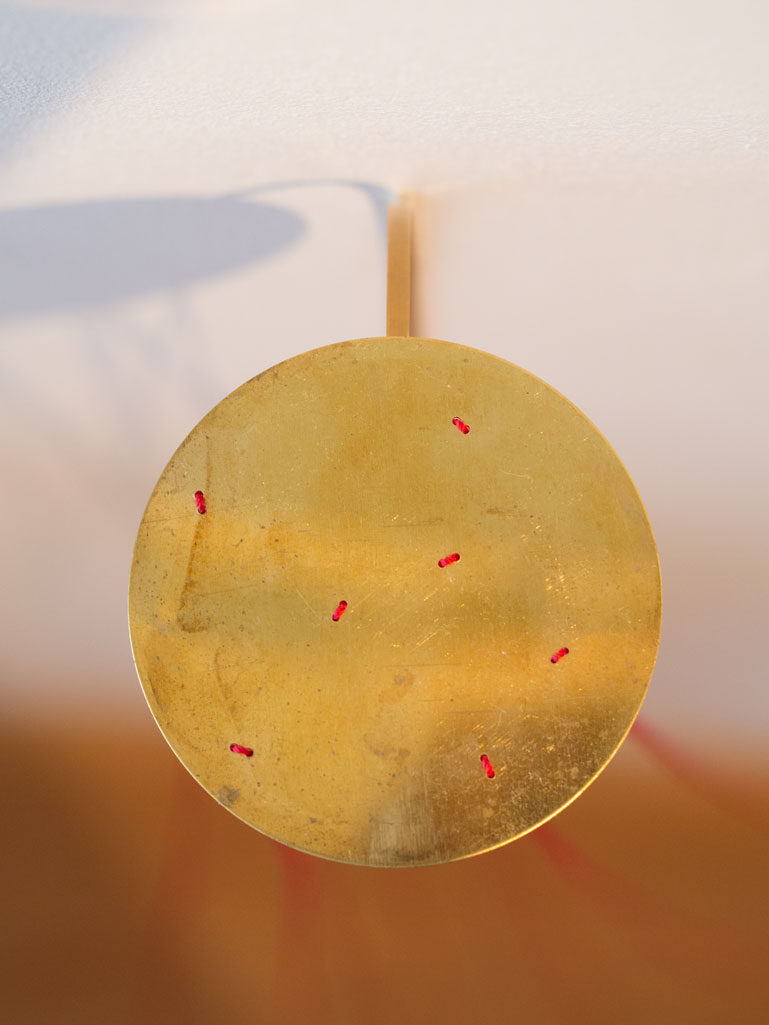 ANJA ASCHE. Oberfläche – Installation, Messingscheibe, Messingstab, roter Faden, Masse variabel, 2021. Surface – Installation, brass disc, brass rod, red thread,
   mass variable, 2021 