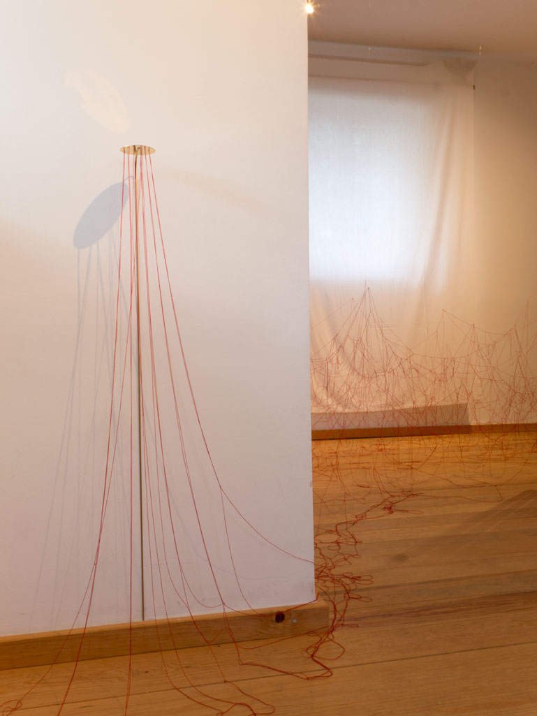 ANJA ASCHE. Oberfläche – Installation, Messingscheibe, Messingstab, roter Faden, Masse variabel, 2021. Surface – Installation, brass disc, brass rod, red thread,
   mass variable, 2021 